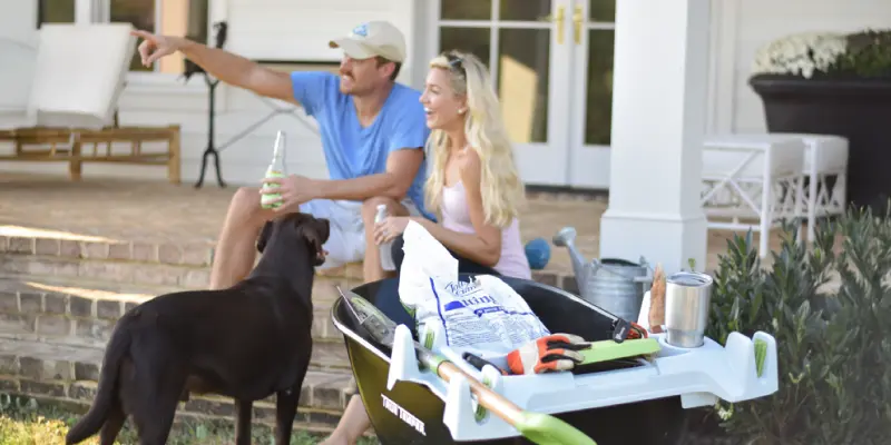 couple on porch with dog and burro buddy on wheelbarrow